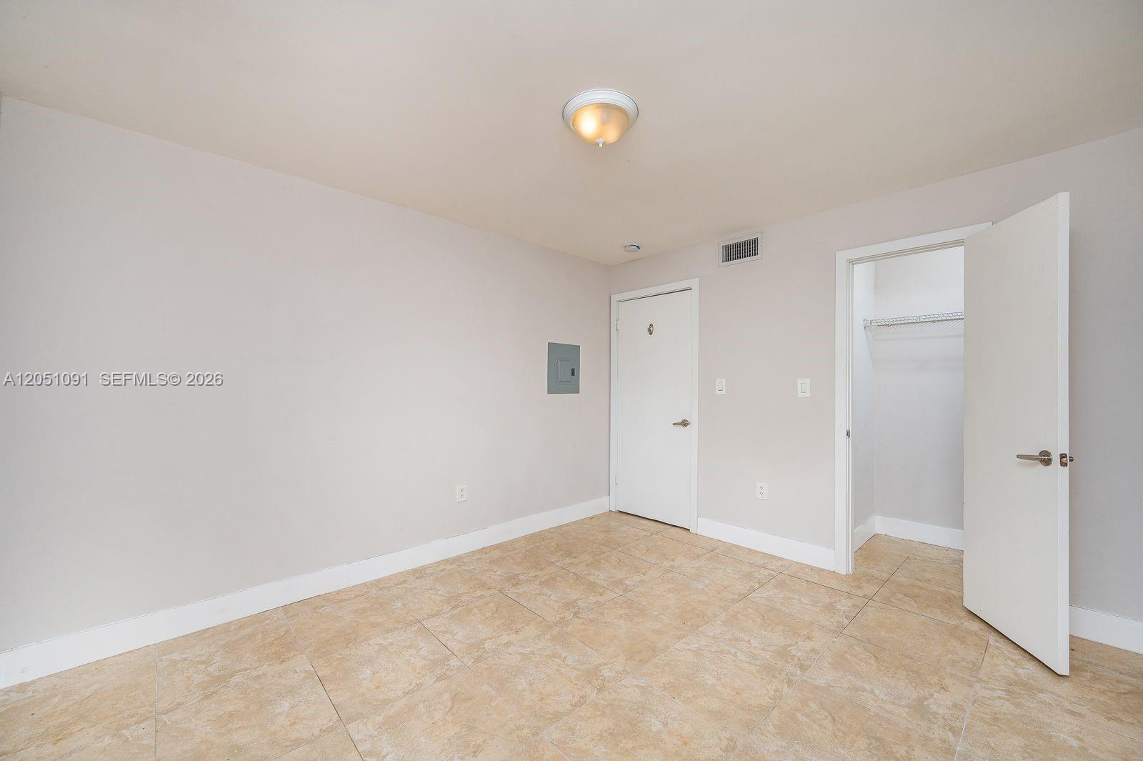 An empty room features light-colored walls, tile flooring, a ceiling light, and an open closet — 15560 SW 104th Ter # 629, Miami FL 33196, MIAMI, FL