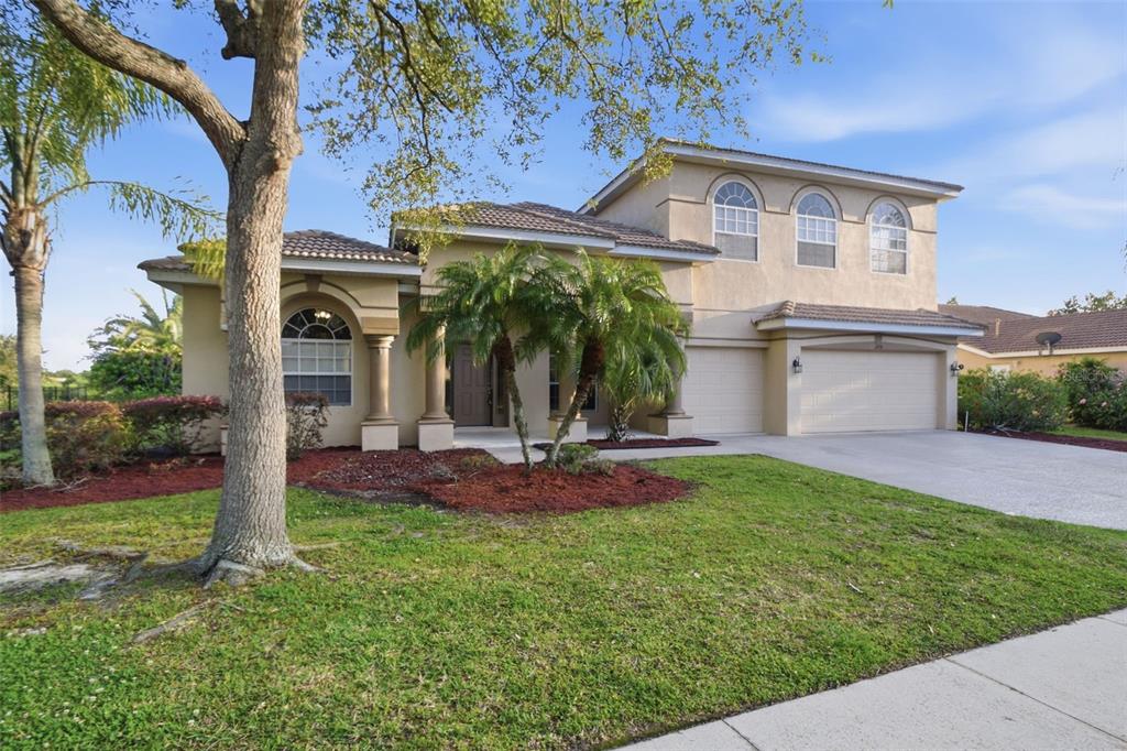 A two-story suburban house with a tan stucco exterior, arched windows, and a two-car garage — 12408 NATUREVIEW CIRCLE, BRADENTON, FL