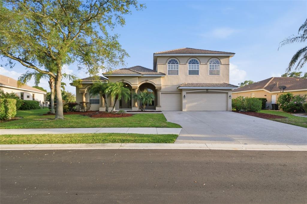 A two-story suburban house with a beige stucco exterior, tile roof, and three-car garage — 12408 NATUREVIEW CIRCLE, BRADENTON, FL