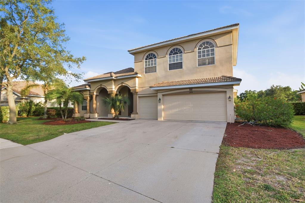 A two-story stucco house with a three-car garage and arched windows under a tile roof — 12408 NATUREVIEW CIRCLE, BRADENTON, FL