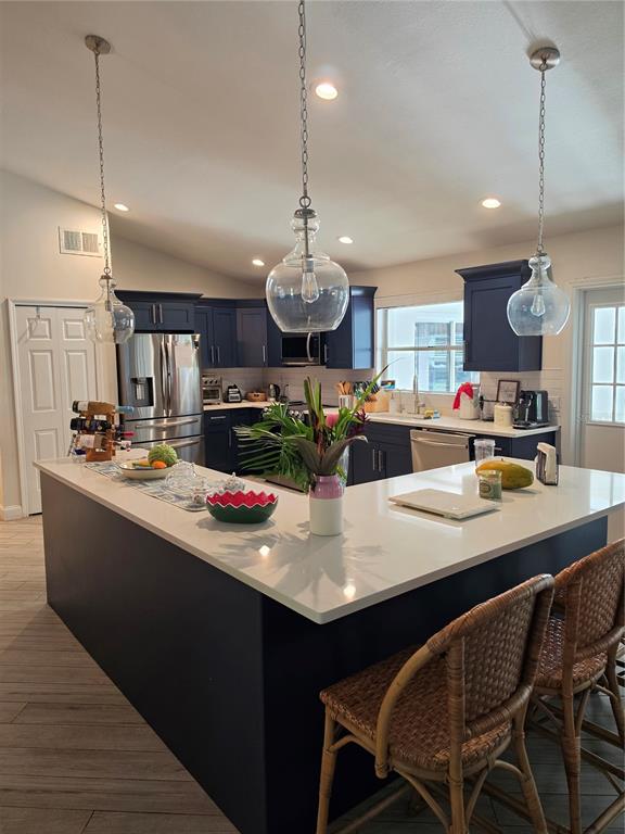 A kitchen features a large white-topped island, navy blue cabinetry, and three glass pendant lights — 10158 BRANDON CIRCLE, ORLANDO, FL