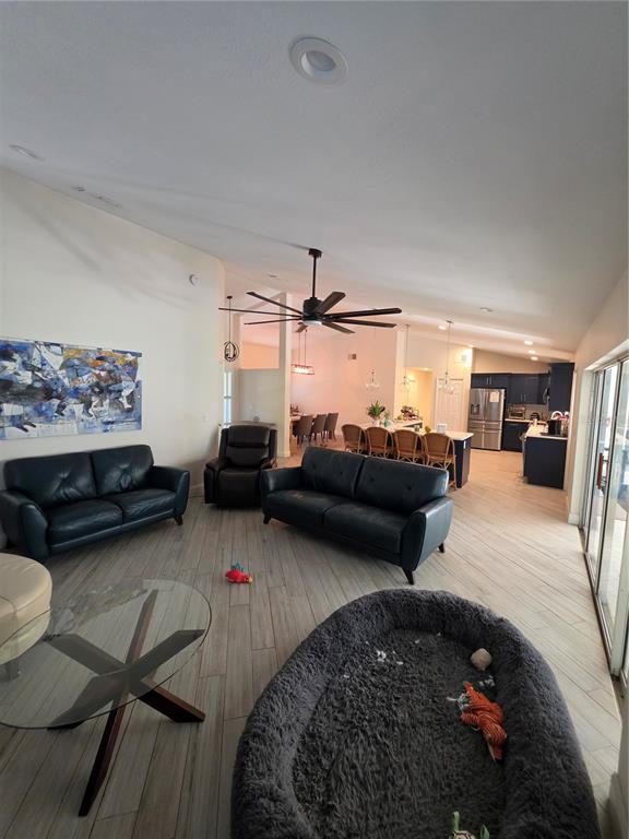 A living room with dark leather sofas, a glass coffee table, and an open kitchen — 10158 BRANDON CIRCLE, ORLANDO, FL