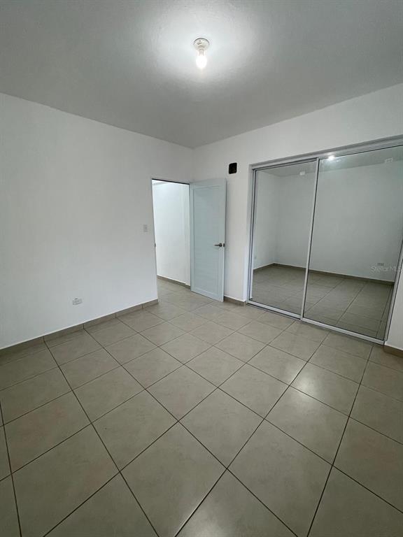 An empty bedroom features light-colored tile flooring, white walls, a closet with mirrored sliding doors — CARR 416 INT CALLE C UNIT 1, AGUADA, PR