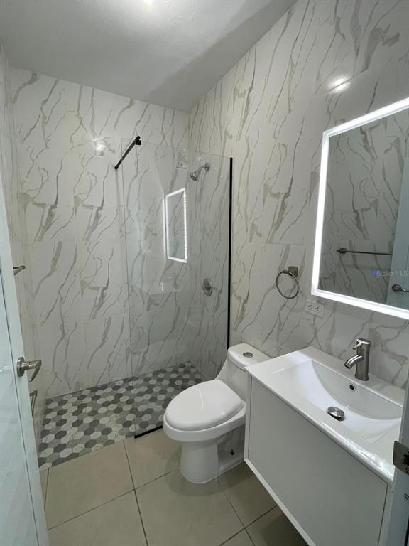 A modern bathroom features marble-patterned wall tiles, a glass-enclosed shower, and a white vanity — CARR 416 INT CALLE C UNIT 1, AGUADA, PR