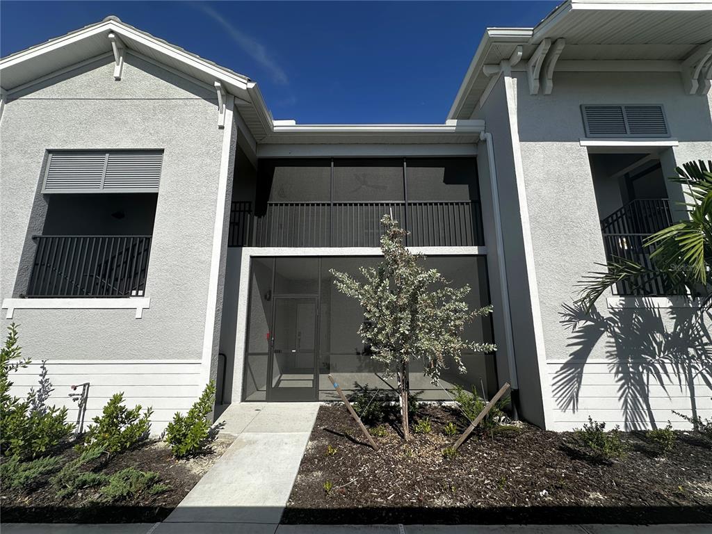 A two-story building exterior features a screened-in entryway and a small tree in front — 14221 HERITAGE LANDING BOULEVARD UNIT 2021, PUNTA GORDA, FL