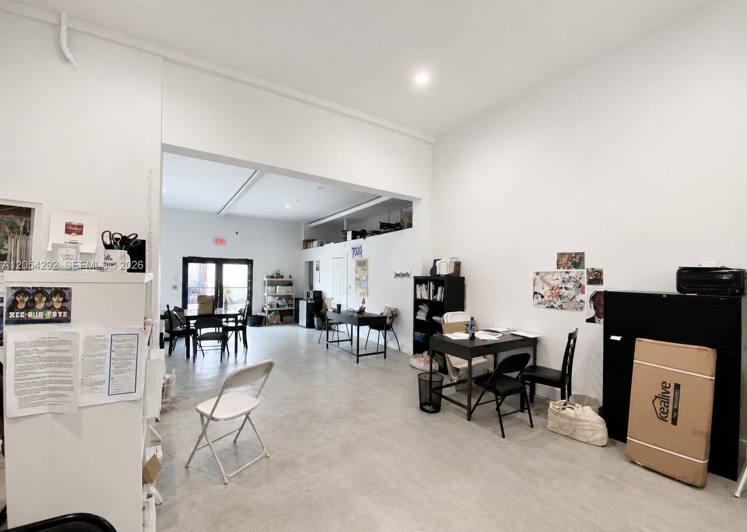 An open-plan office space with white walls, concrete floors, and multiple desks and chairs — 7000 NW 2 Ave # 7060, Miami FL 33150, MIAMI, FL