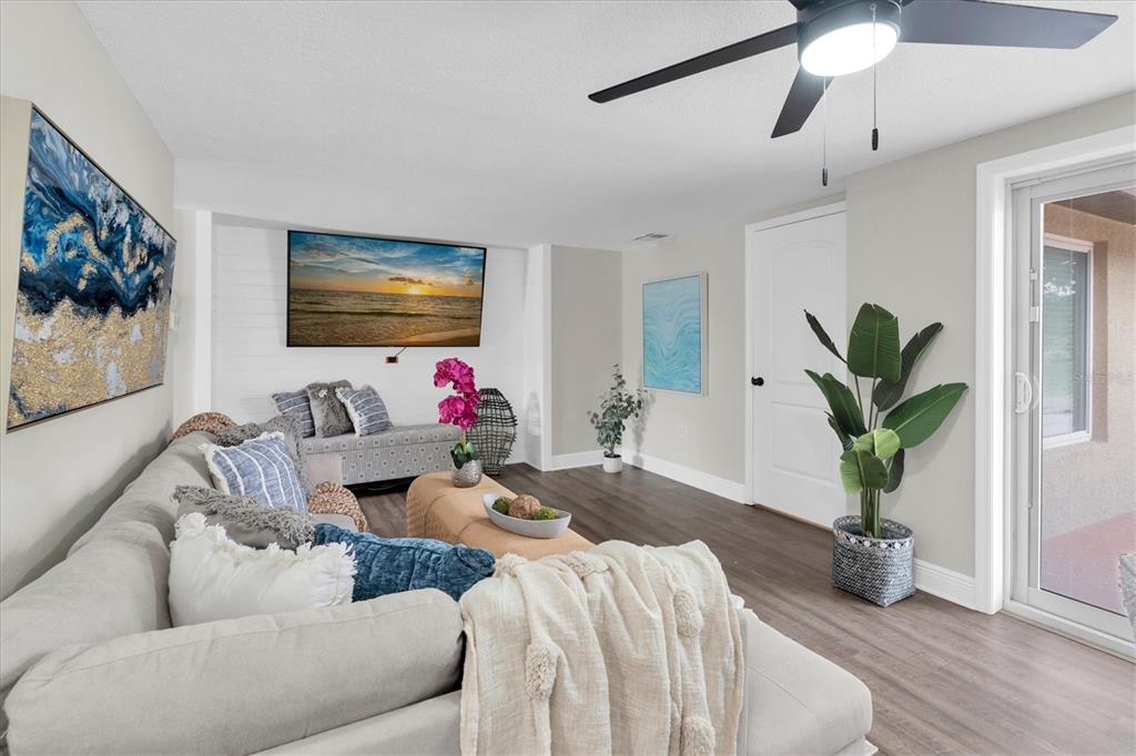 A living room features a sectional sofa, a wall-mounted television, and a sliding glass door — 8007 MIMOSA DRIVE, PORT RICHEY, FL