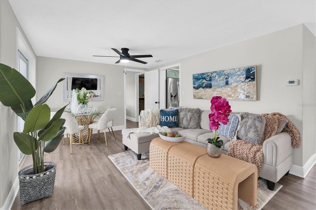 A living room features a sectional sofa, a dining set, and light wood-look flooring — 8007 MIMOSA DRIVE, PORT RICHEY, FL
