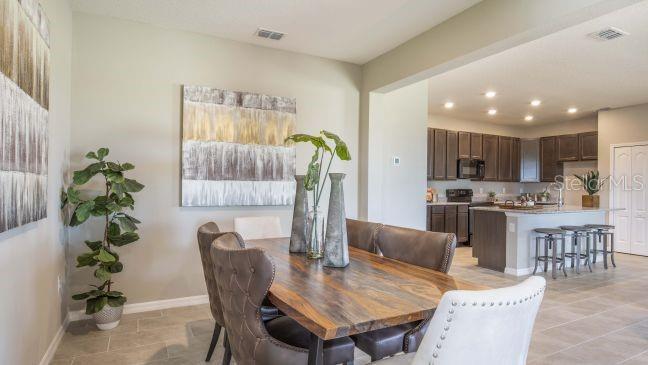 A dining area with a wooden table and chairs sits adjacent to an open-concept kitchen — 25125 THORNHILL DRIVE, SORRENTO, FL