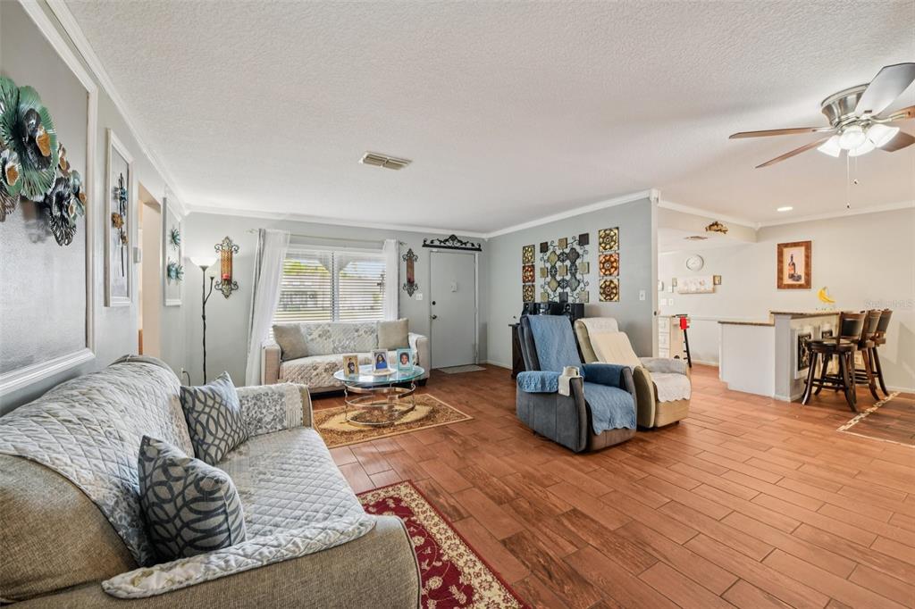 A living room features tile flooring, a ceiling fan, and an open kitchen area — 10407 LARISSA STREET, ORLANDO, FL