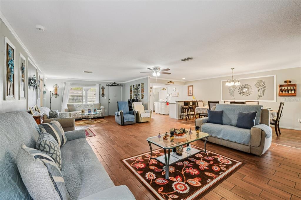 A spacious living room features tile flooring, two sofas, a glass coffee table, and dining area — 10407 LARISSA STREET, ORLANDO, FL