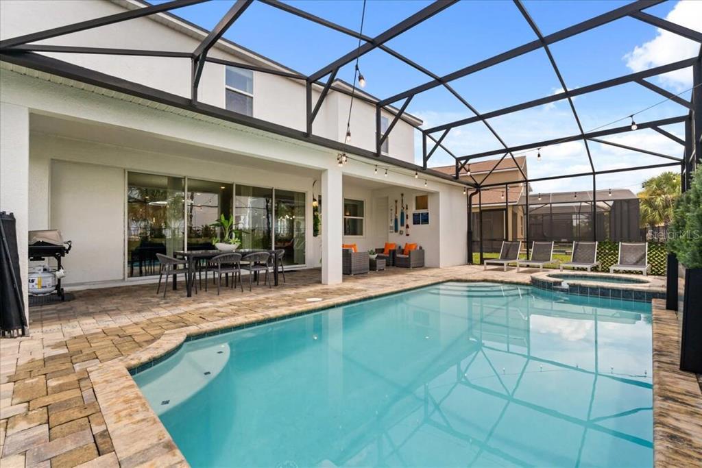 A screened-in patio features a swimming pool, a hot tub, and outdoor dining furniture — 1582 MERMAID COVE WAY, KISSIMMEE, FL