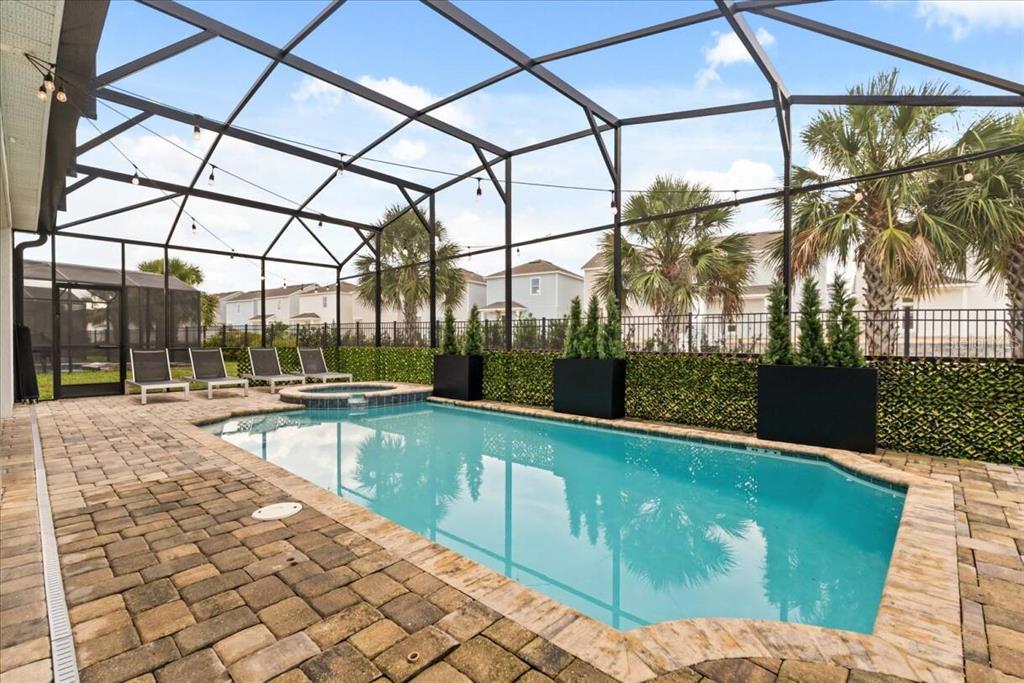 A screened-in swimming pool with a hot tub and patio furniture on a paver deck — 1582 MERMAID COVE WAY, KISSIMMEE, FL