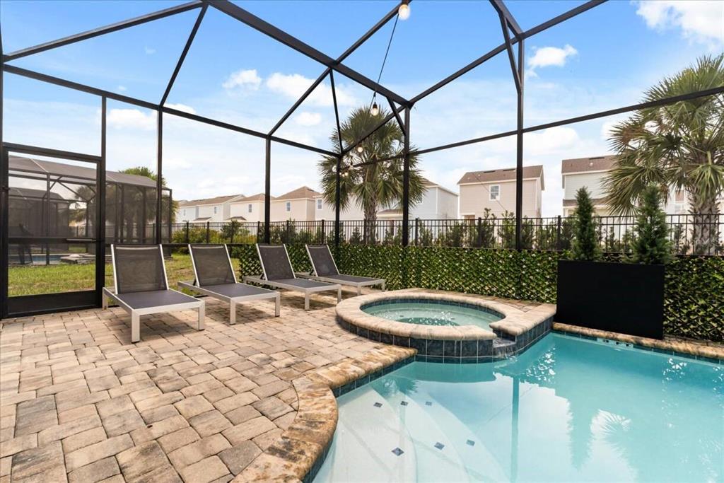 A screened-in patio features a swimming pool, a raised hot tub, and four lounge chairs — 1582 MERMAID COVE WAY, KISSIMMEE, FL