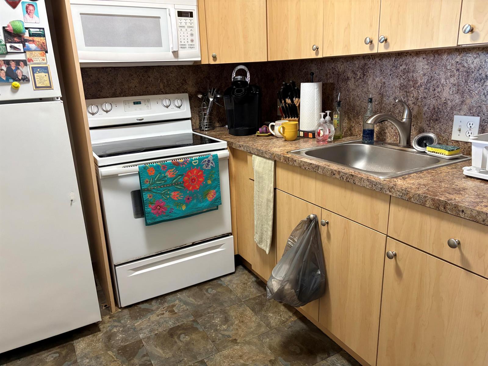 A kitchen features light wood cabinets, a white stove, a microwave, and a stainless sink — 314 Preston H, Boca Raton FL 33434, BOCA RATON, FL