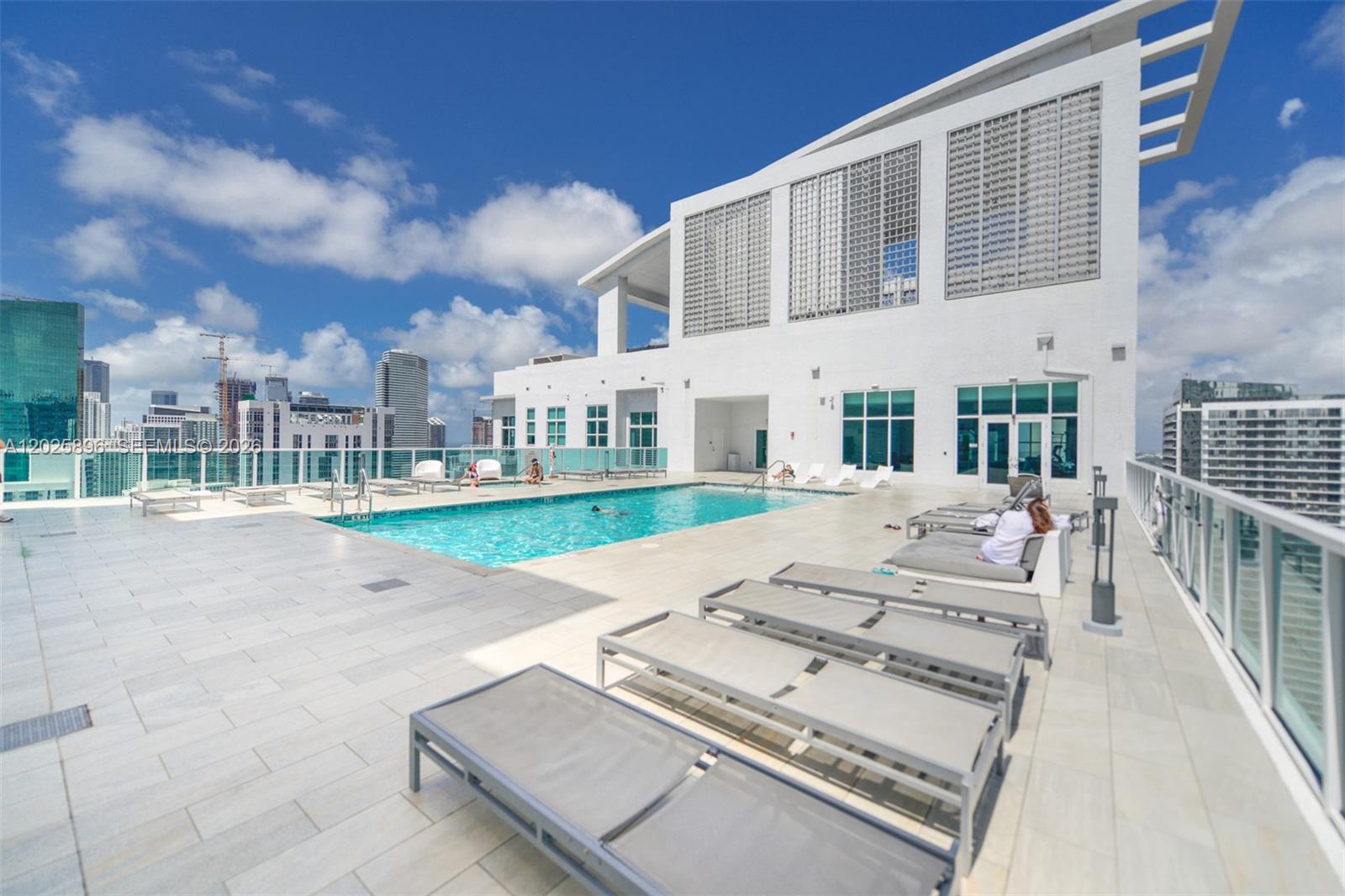 A rooftop swimming pool area features lounge chairs on a tiled deck with city views — 133 NE 2nd Ave # 1512, Miami FL 33132, MIAMI, FL