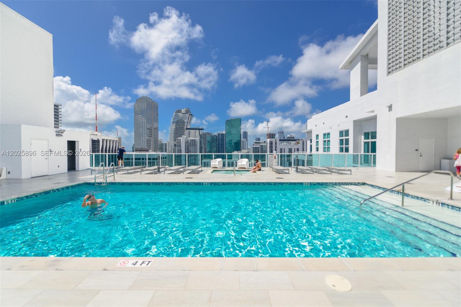 A rooftop swimming pool overlooks a city skyline under a bright blue sky — 133 NE 2nd Ave # 1512, Miami FL 33132, MIAMI, FL