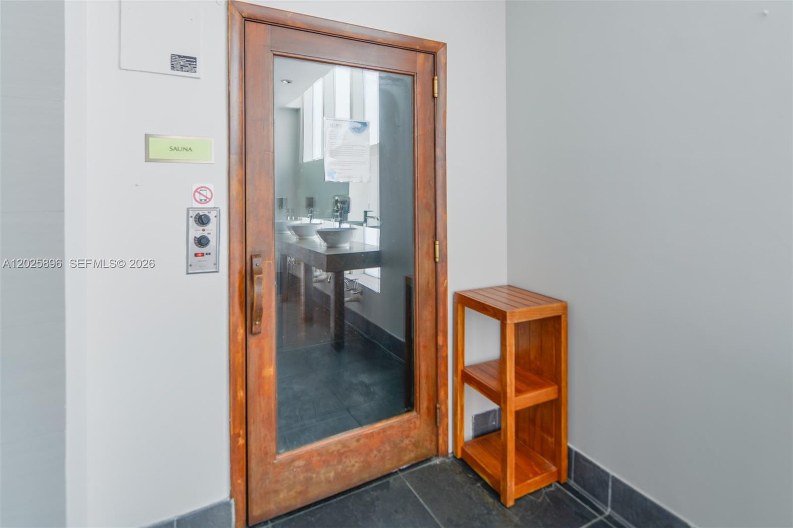 A wooden door with a glass panel leads to a sauna with a vanity inside — 133 NE 2nd Ave # 1512, Miami FL 33132, MIAMI, FL