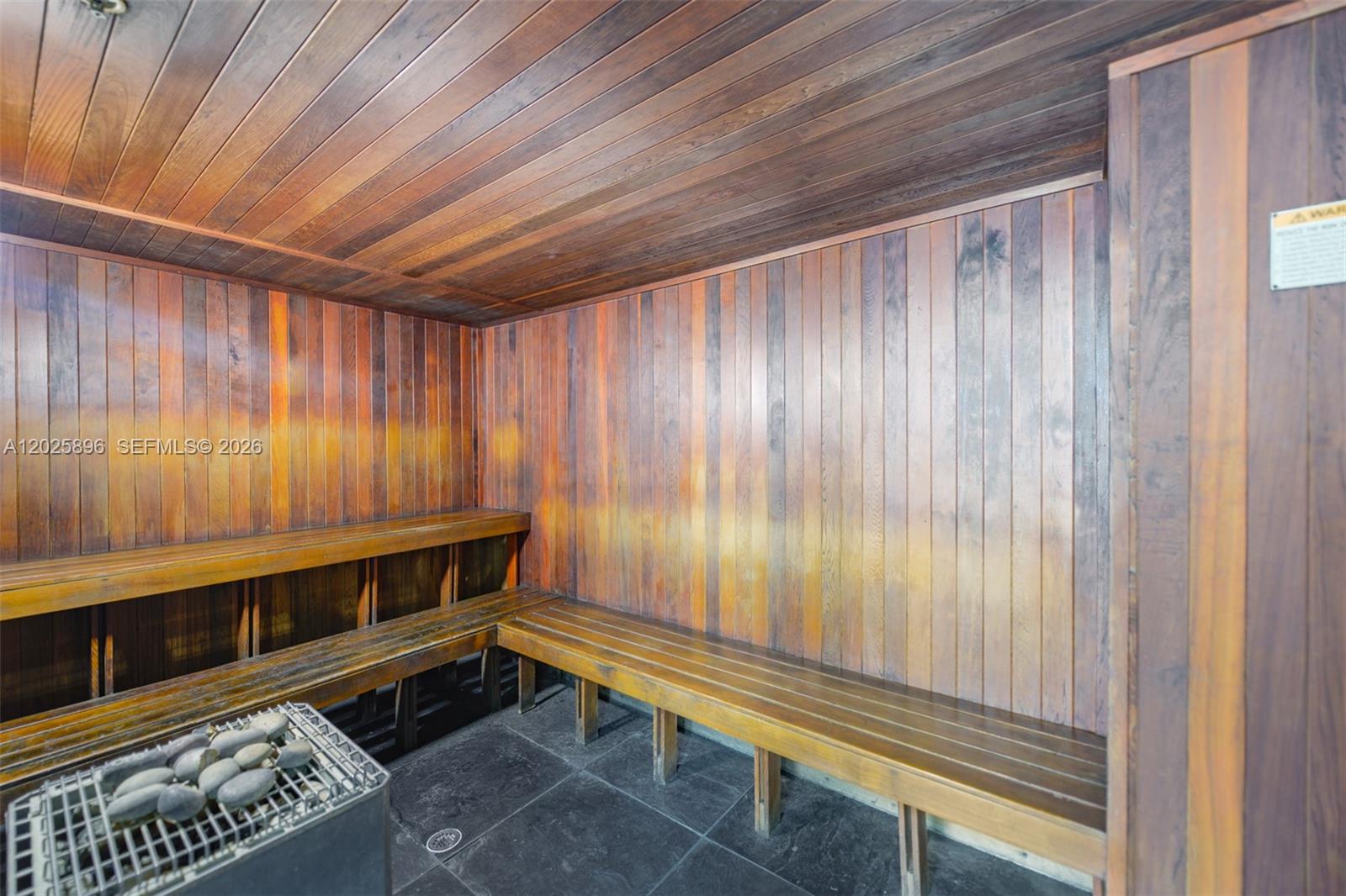 A wood-paneled sauna features tiered bench seating and a metal heater with stones — 133 NE 2nd Ave # 1512, Miami FL 33132, MIAMI, FL