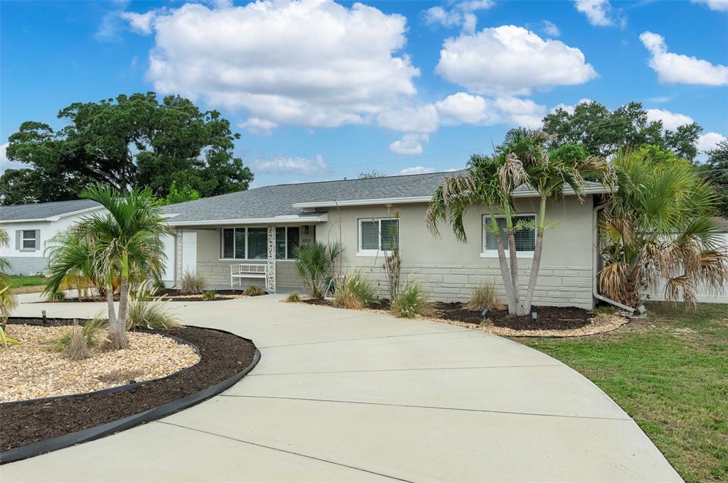 A single-story house with a curved concrete driveway, palm trees, and a gray exterior — 6355 23RD AVENUE N, ST PETERSBURG, FL