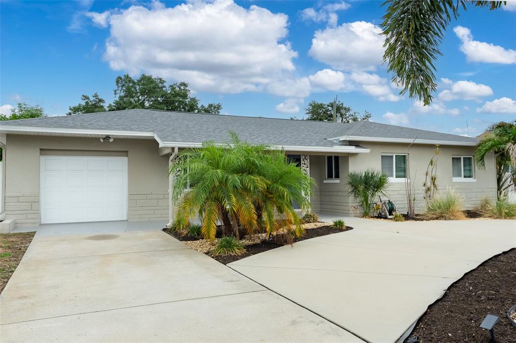 A single-story house with a gray roof, beige exterior, attached garage, and a palm tree — 6355 23RD AVENUE N, ST PETERSBURG, FL