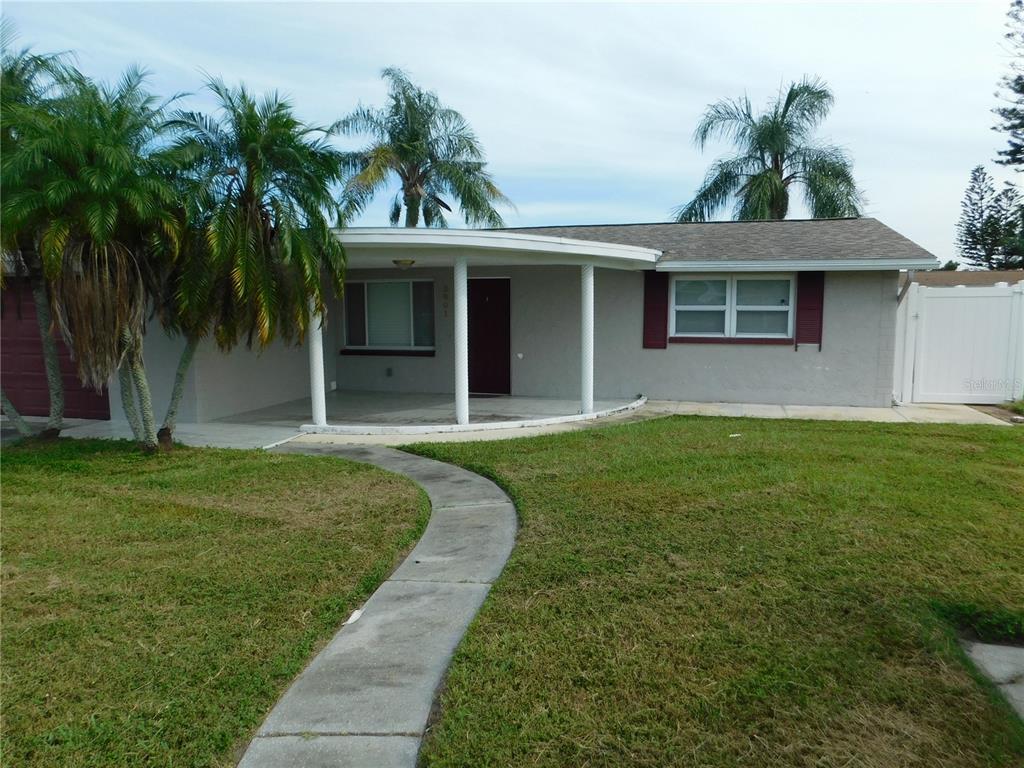 A single-story house with a curved porch, palm trees, and a concrete walkway — 3801 DARLINGTON ROAD, HOLIDAY, FL