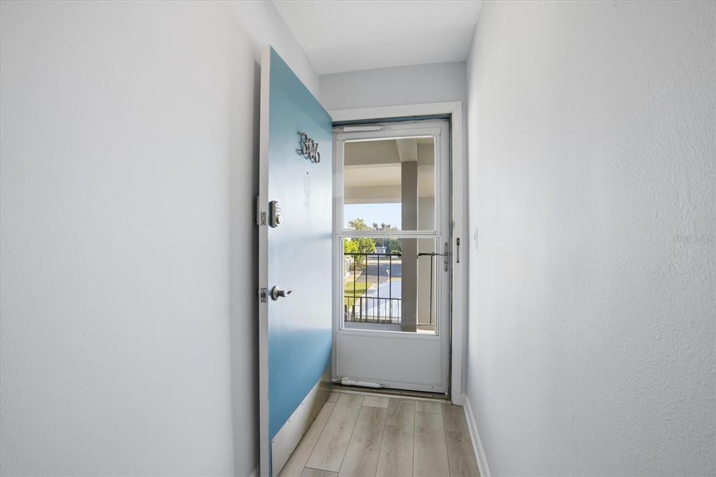 An open blue door reveals a view of an outdoor walkway and a parking area — 649 TAMIAMI TRAIL S UNIT 306, VENICE, FL