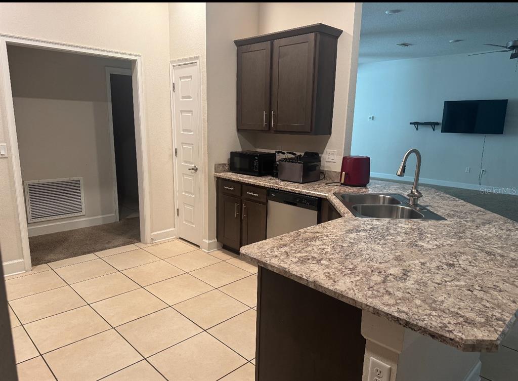 A kitchen with dark wood cabinets, granite-look countertops, a double sink, and tile flooring — 333 ASHTON WOODS LANE, LEESBURG, FL