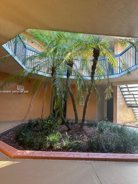 An outdoor courtyard features a central palm tree surrounded by low plants and staircases — 6288 NW 186th St # 112, Hialeah FL 33015, HIALEAH, FL