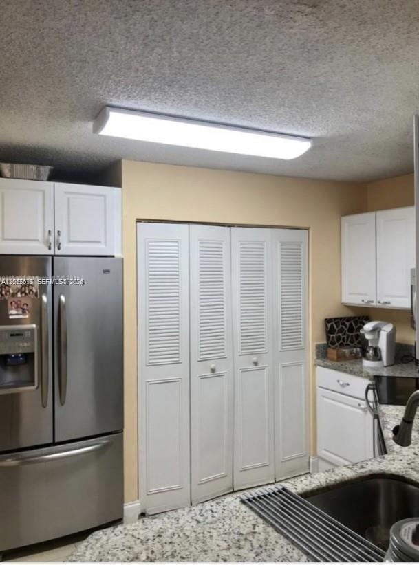 A kitchen features white cabinetry, stainless steel appliances, granite countertops, and louvered closet doors — 6288 NW 186th St # 112, Hialeah FL 33015, HIALEAH, FL