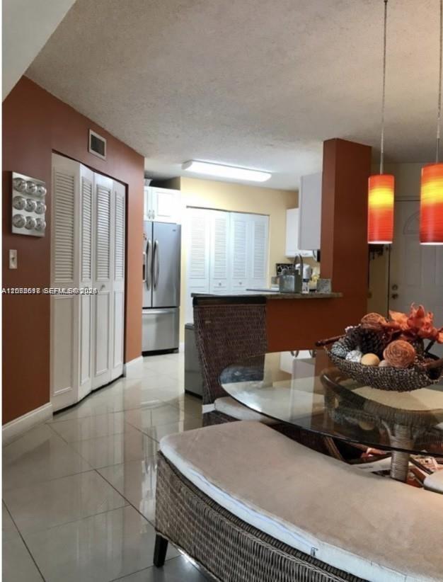 A dining area with a glass table and wicker bench leads into a kitchen with stainless appliances — 6288 NW 186th St # 112, Hialeah FL 33015, HIALEAH, FL