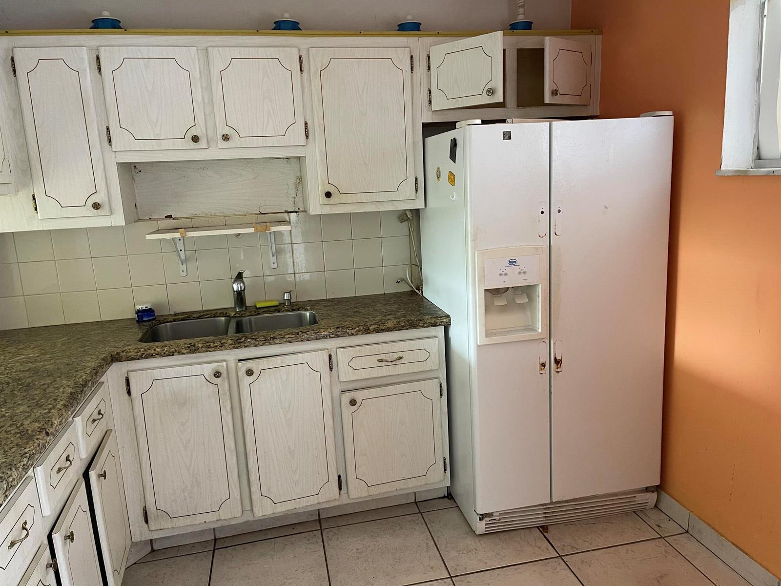 A kitchen features white cabinets, a granite countertop, a double sink, and a white refrigerator — 2606 Garden Drive S # 107, FL 33461, FL