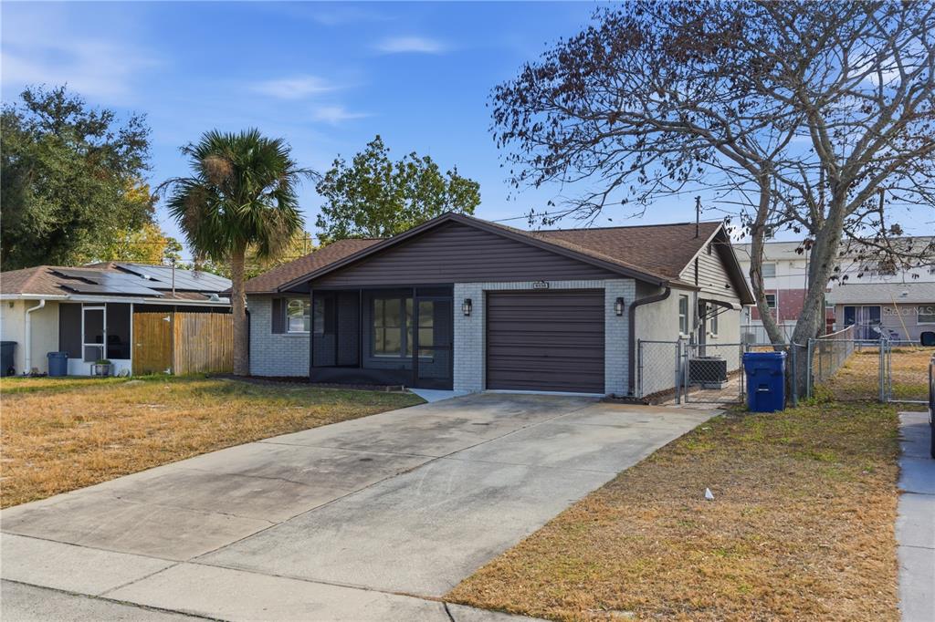A single-story house with a brown garage door, a screened porch, and a concrete driveway — 5330 POINSETTIA DR, NEW PORT RICHEY, FL