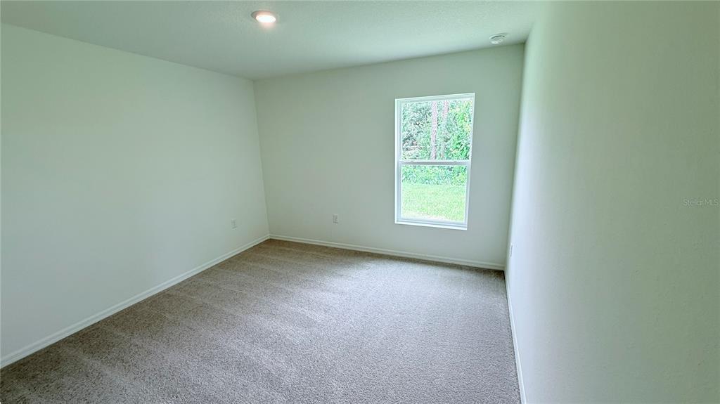 An empty bedroom features light-colored walls, beige carpeting, and a single window — 234 BEECHWOOD LANE, PALM COAST, FL