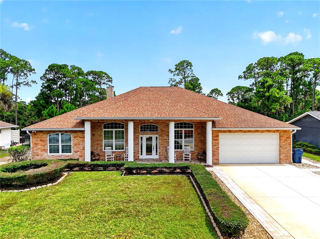 A single-story brick house with a hip roof, white columns, and a two-car garage — 108 GODFREY ROAD, EDGEWATER, FL