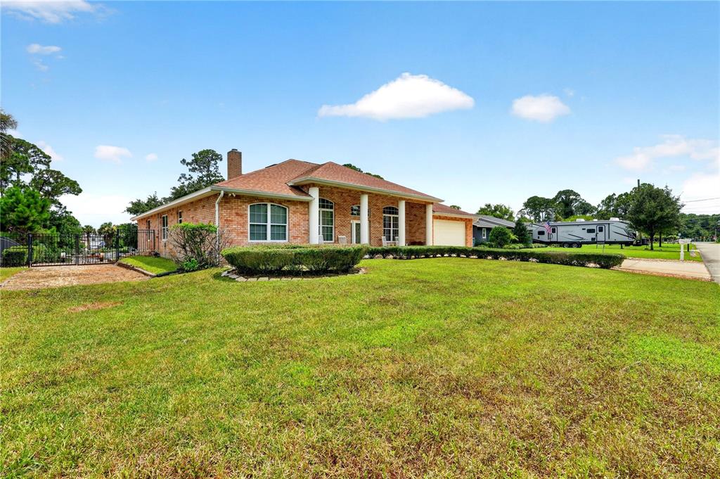 A single-story brick house with a covered front porch sits on a large grassy lot — 108 GODFREY ROAD, EDGEWATER, FL