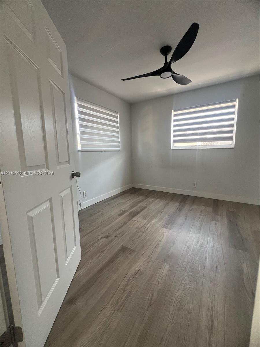 A bedroom features light gray walls, wood-look flooring, two windows with blinds, and a ceiling fan — 1711 Thomas St, Hollywood FL 33020, HOLLYWOOD, FL