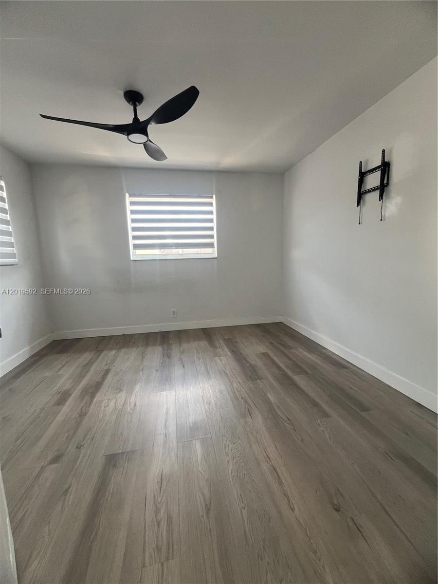 This bedroom features light gray wood-look flooring, white walls, a ceiling fan, and a window — 1711 Thomas St, Hollywood FL 33020, HOLLYWOOD, FL