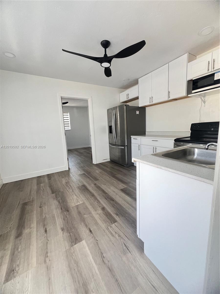 A kitchen features white cabinets, stainless steel appliances, and light wood-look flooring — 1711 Thomas St, Hollywood FL 33020, HOLLYWOOD, FL