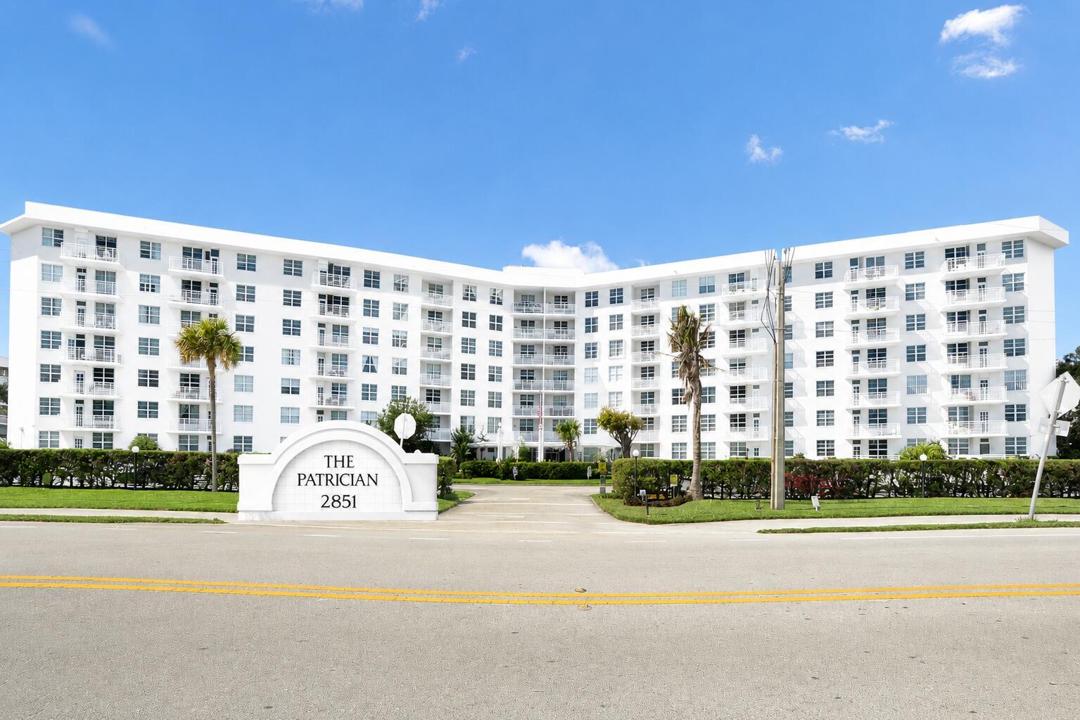 A white, multi-story apartment building with balconies stands behind a sign and a paved driveway — 2851 S Ocean Boulevard # 7s, Boca Raton FL 33432, BOCA RATON, FL