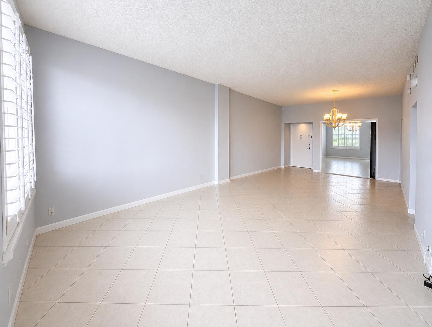 An empty room with light gray walls, beige tile flooring, and a chandelier — 2851 S Ocean Boulevard # 7s, Boca Raton FL 33432, BOCA RATON, FL