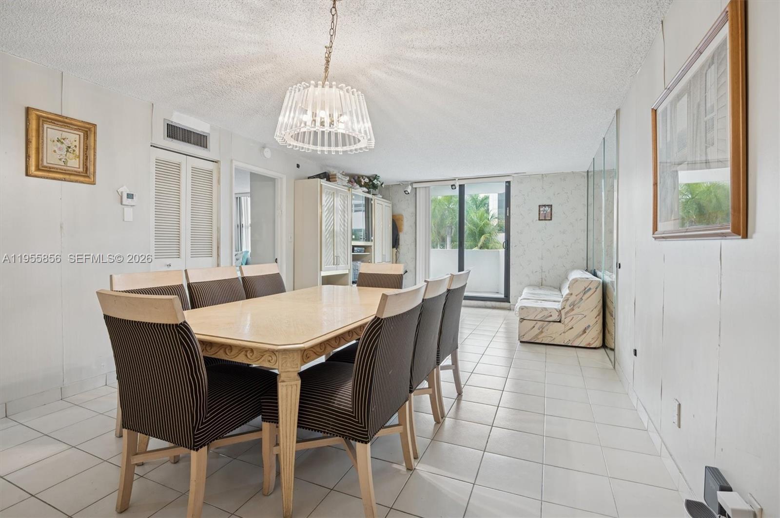 A dining area features a wooden table, striped chairs, a chandelier, and tiled flooring — 4301 Collins Ave # 202, Miami Beach FL 33140, MIAMI BEACH, FL