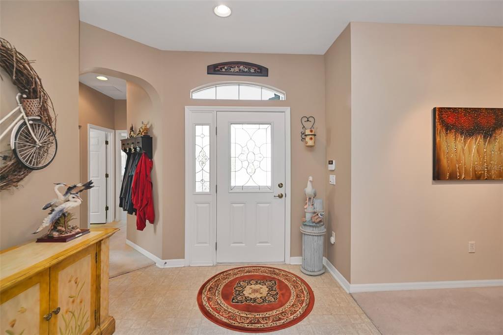 A bright entryway features a white front door, tile flooring, and a round area rug — 7981 SW 81ST LOOP, OCALA, FL