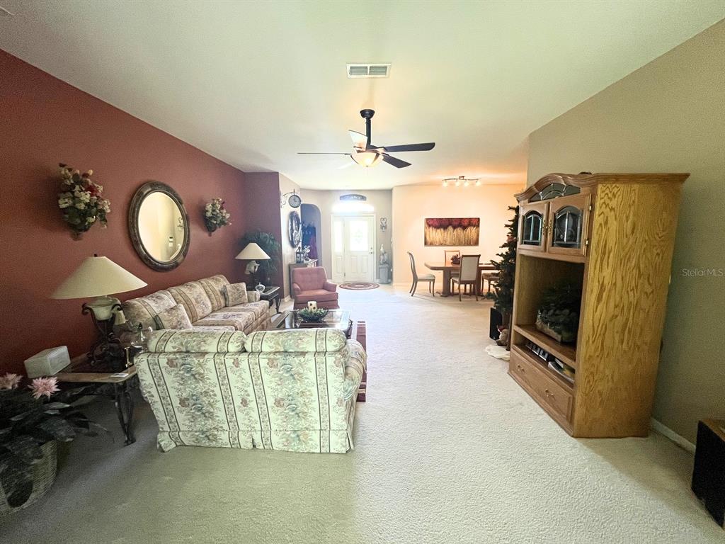 A living room with floral sofas, a large wooden entertainment center, and a dining area — 7981 SW 81ST LOOP, OCALA, FL