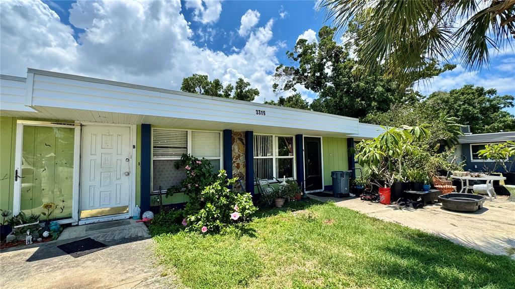 The exterior of a single-story residential building features a white door and green siding — 3319 SHERWOOD DRIVE, LARGO, FL