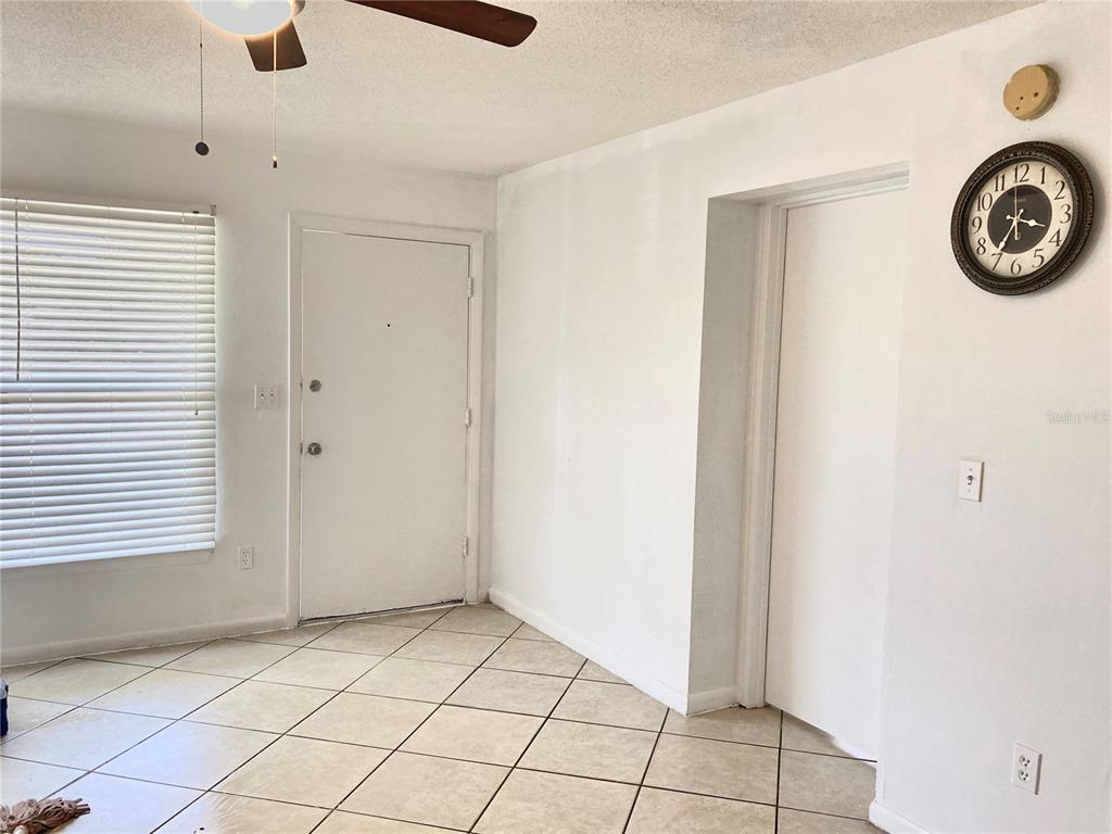 A room with tiled floors, a white door, a ceiling fan, and a wall clock — 3319 SHERWOOD DRIVE, LARGO, FL