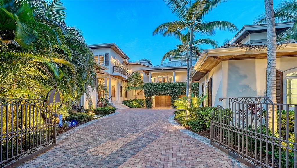 A paved driveway leads to the entrance of a large, multi-story house with tropical landscaping — 1435 WESTWAY DRIVE, SARASOTA, FL