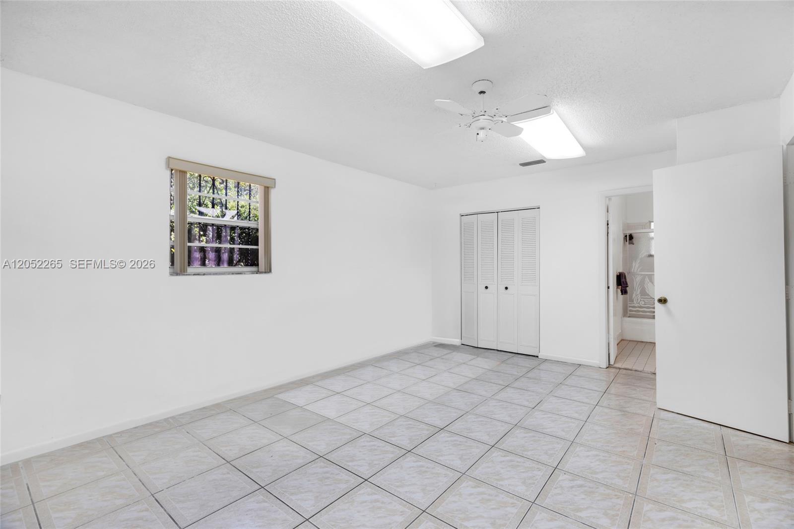 This bedroom features white walls, tiled flooring, a ceiling fan, and an attached bathroom — 16420 NE 5th Ave # 000, Miami FL 33162, MIAMI, FL