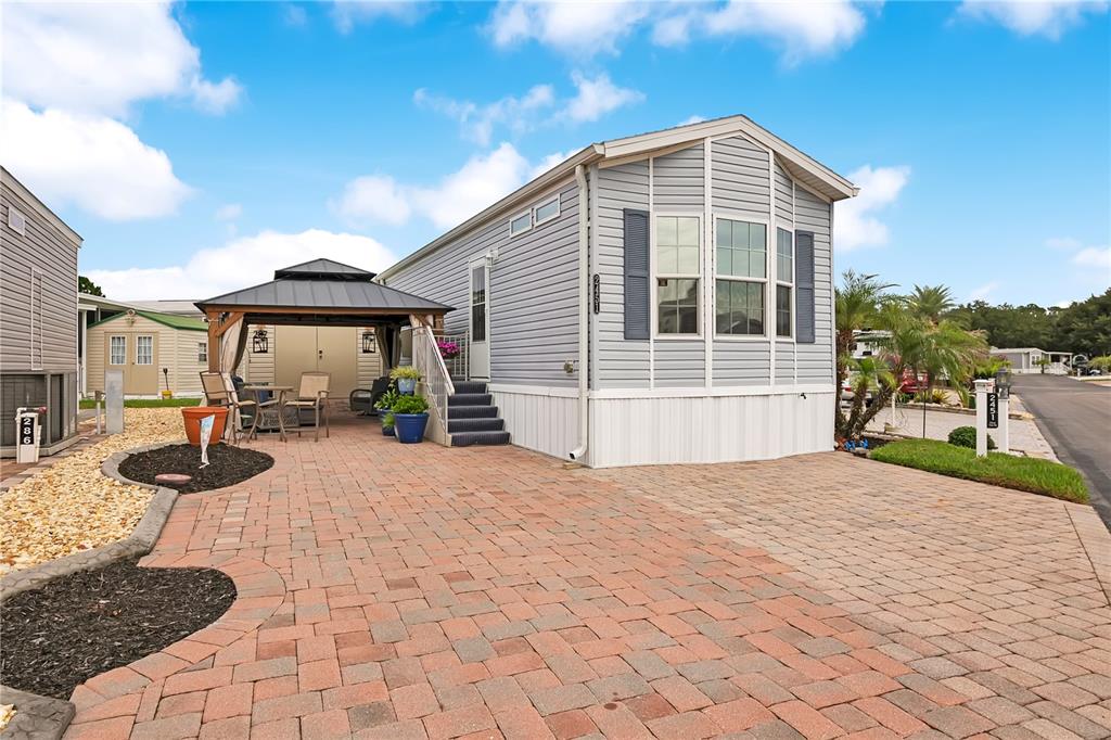 A light blue manufactured home features a brick paver driveway and a covered outdoor gazebo — 2451 CITRUS TREE ROAD, CLERMONT, FL