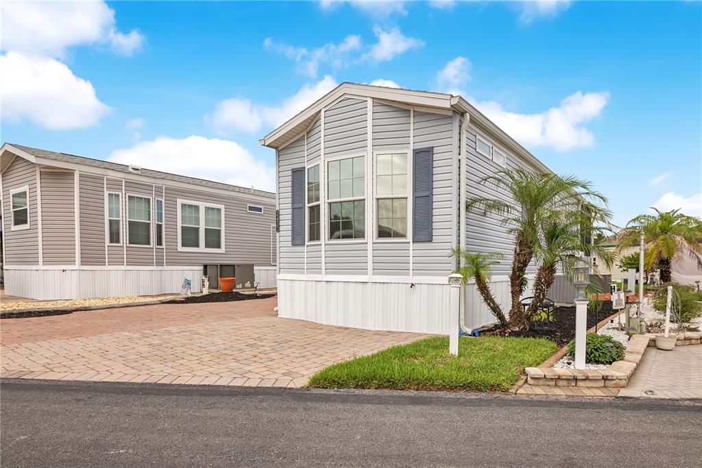 Two light-gray manufactured homes with paved driveways and small palm trees under a blue sky — 2451 CITRUS TREE ROAD, CLERMONT, FL